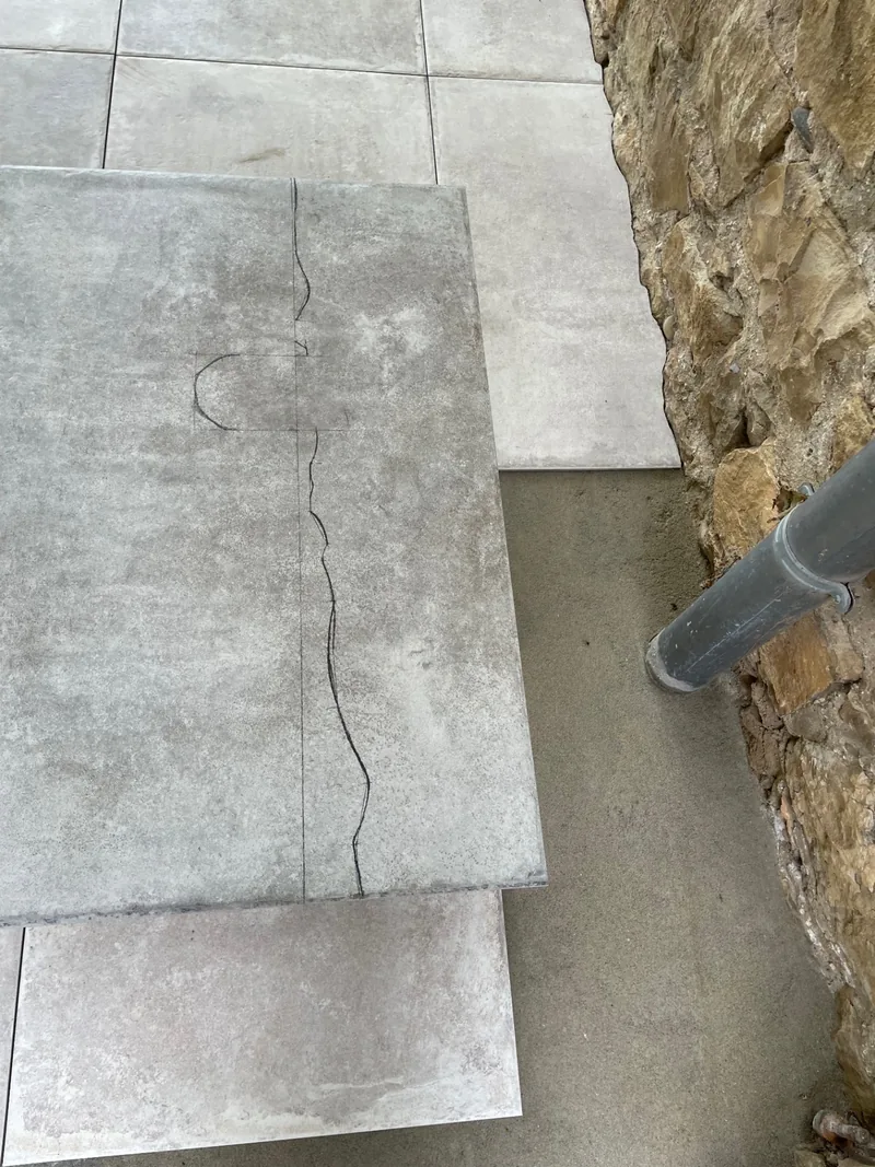Traçage d’une découpe de carrelage au pied du mur en pierre