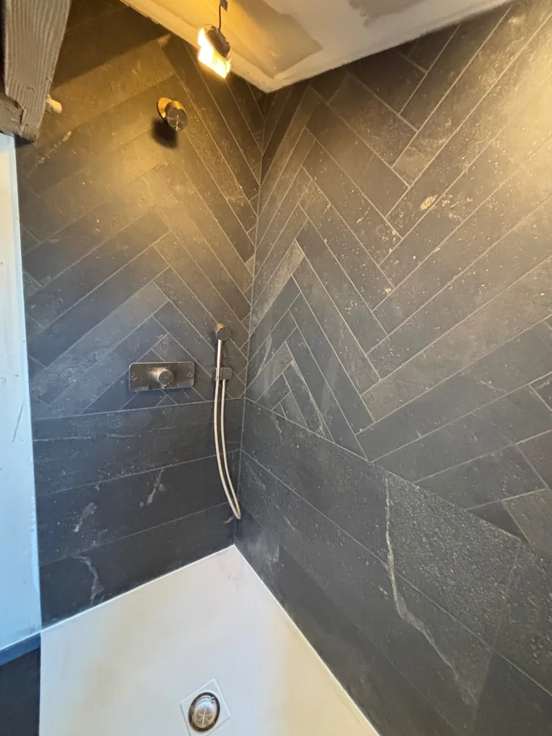 Détail du carrelage sombre posé en chevrons dans la douche à Valence